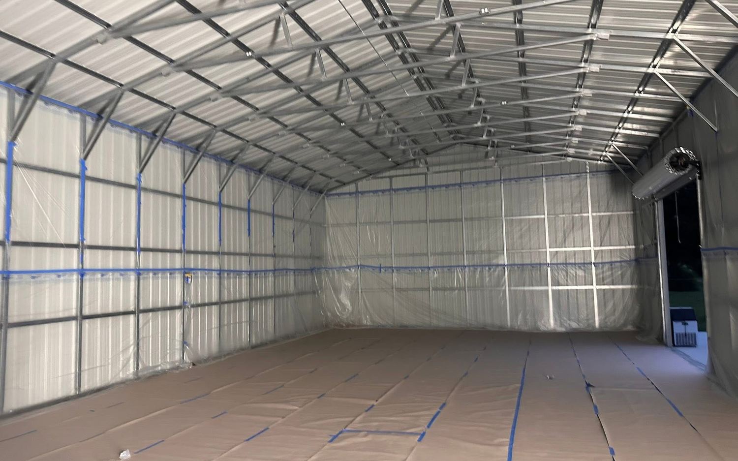 Metal building masked and sheeted before spraying