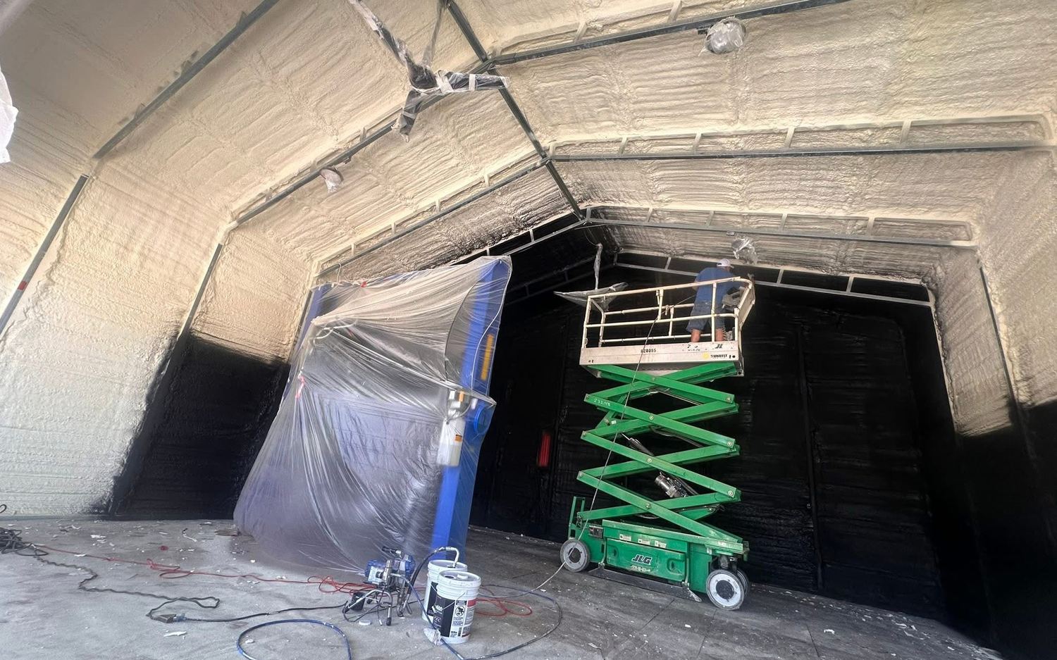 Spraying a warehouse roof deck from a scissor lift