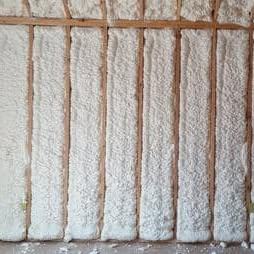Spray foam filling wall cavities between studs
