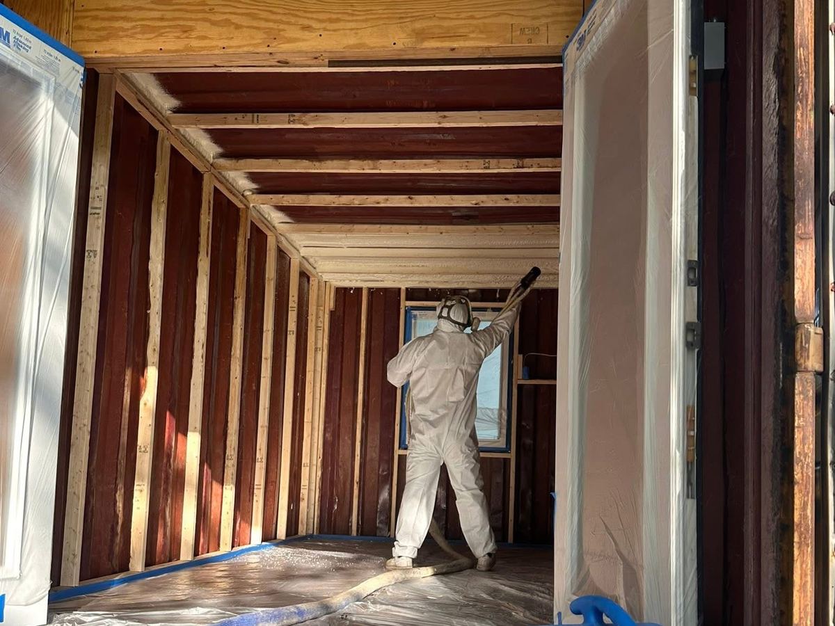 Crew member spraying foam into wall framing